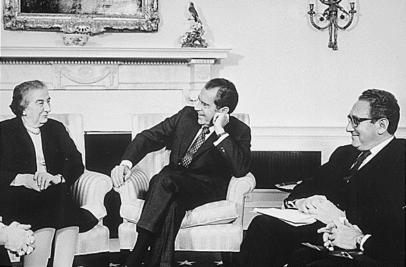 Nixon, Kissinger en Golda Meir, voormalig minister-president van Israël zitten op comfortabele stoelen en praten met elkaar.